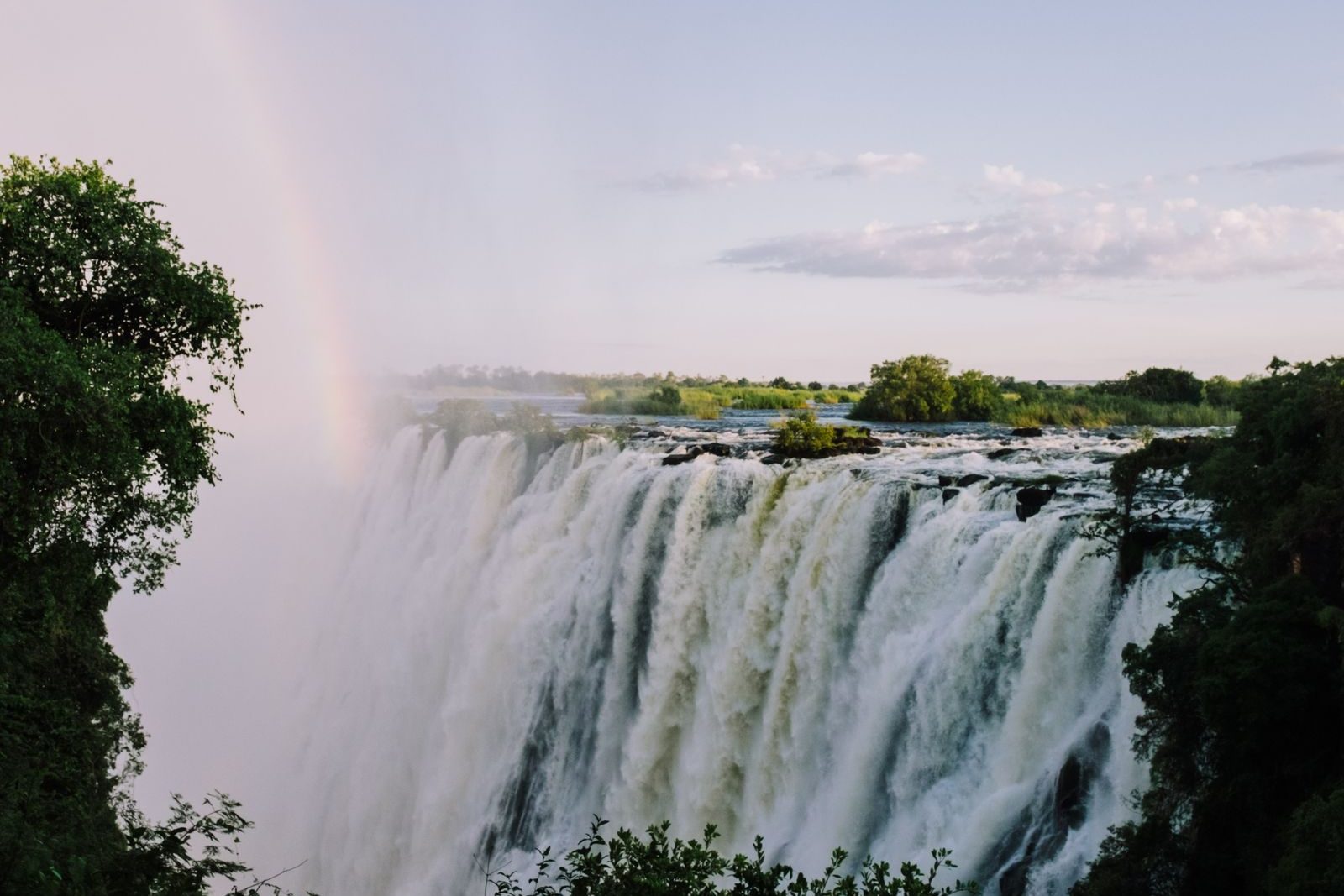 Victoria Falls with a faint rainbow rising from the spray above the Zambezi